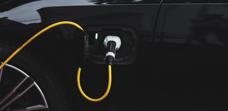 Close up photography of a black car plugged to a charger.