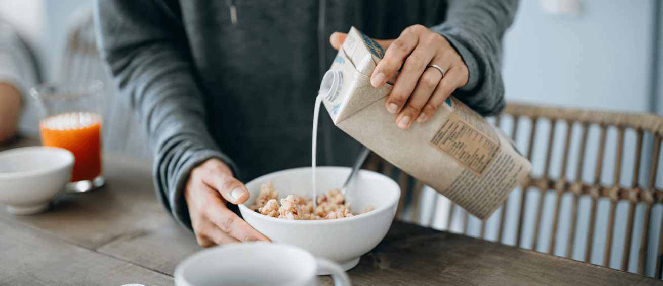 Woman pours milk on cereal before breakfast