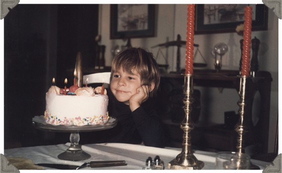 a picture of a boy waiting to blow out his candles of his birthday cake