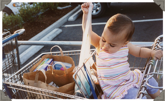 a picture of a toddler on a trolley pulling out grocery