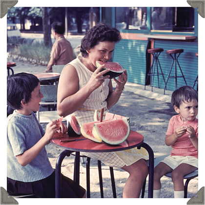 a picture of a woman with two children eating watermelon