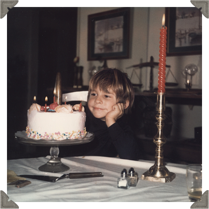 a picture of a boy waiting to blow out his candles of his birthday cake