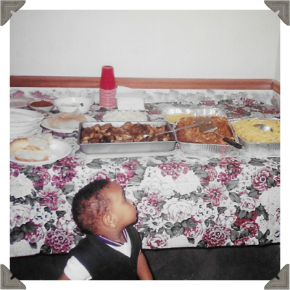 a picture of a toddler looking at a table of food spread