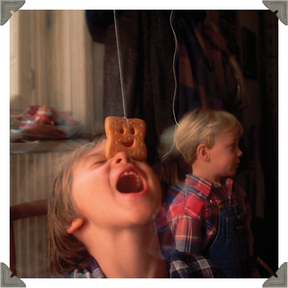 a picture of three children and silly faces with biscuits on their face