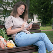 Woman on bench next to bag of fresh produce
