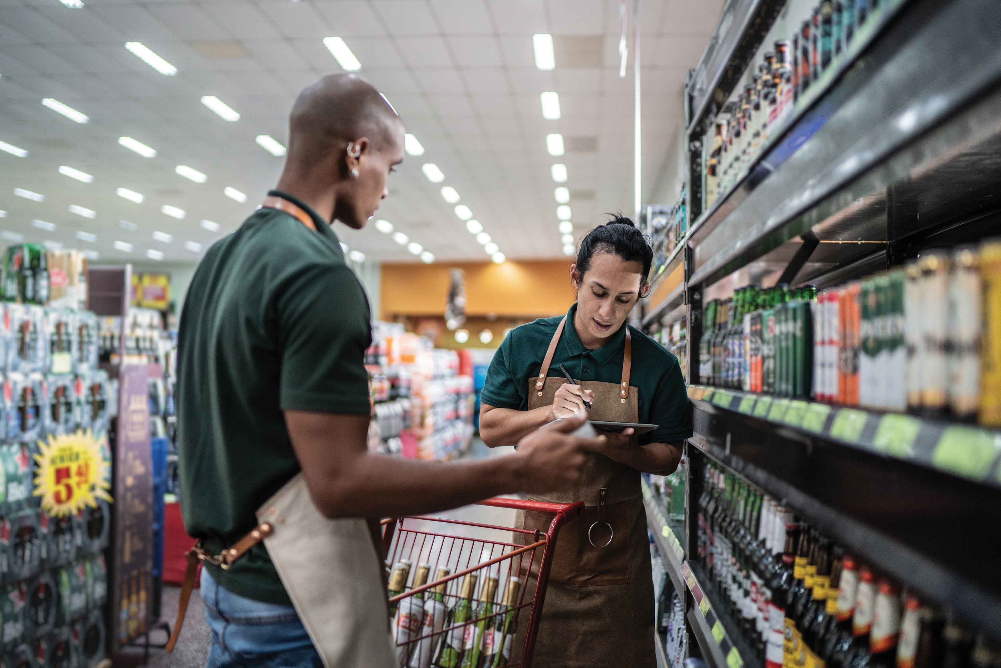 Grocery store employees restocking shelves and looking at iPad