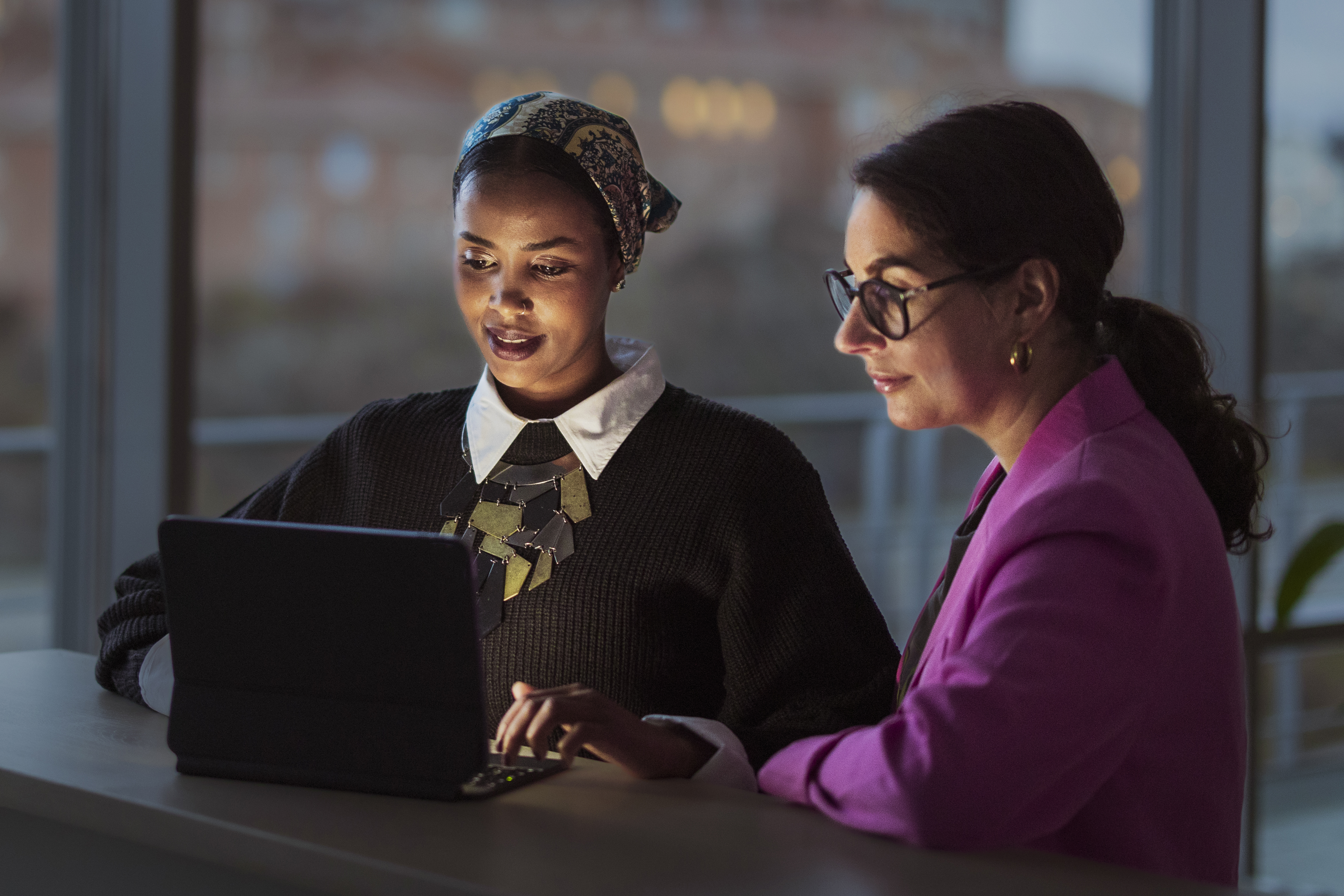 Photo of two women observing the screen of a laptop.